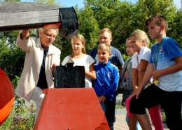 Die HistoryKids werden am 21. September zwei Jahre alt. Vor kurzem trafen sie sich am Alten Schmiedehammer vor der Bibliothek. Hier ließen sich die geschichtsinteressierten Kinder von Helga Ass diesen speziellen Typ Schwanzhammer erklären, an dem sie in der Messerschmiede viele Jahre gearbeitet hatte. (Foto: Liane Protzmann)